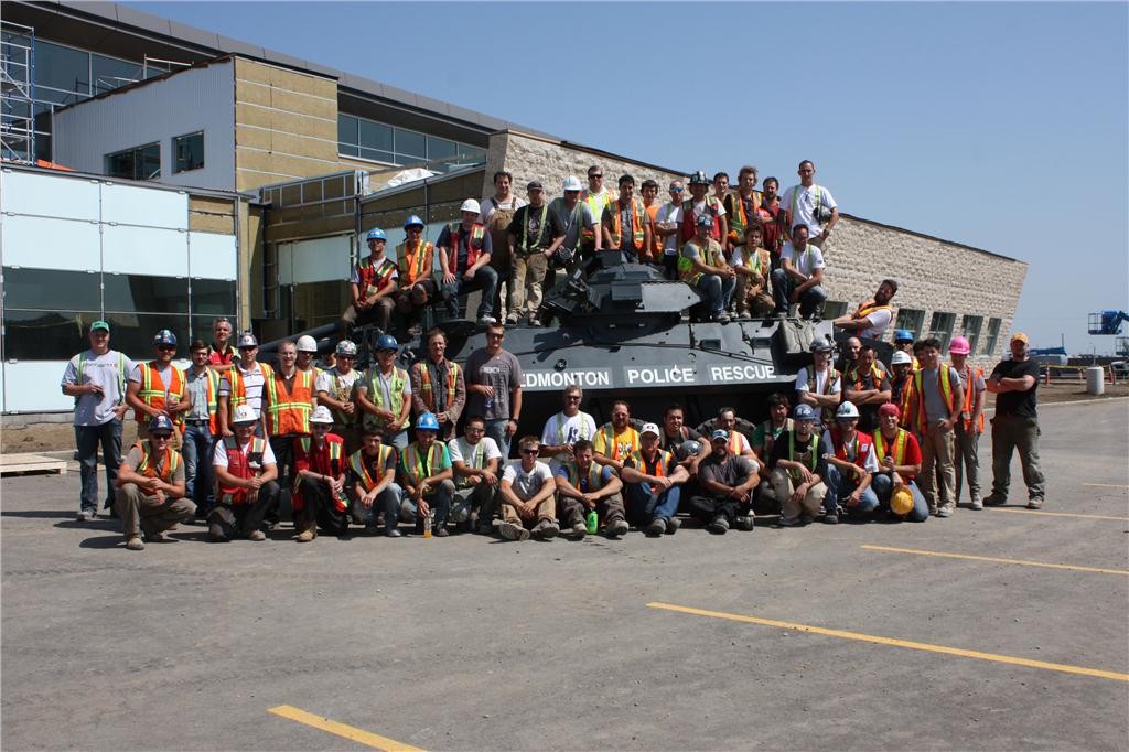 Clark Builders employees take a photo at the site for Edmonton's new Police Services Station during a company barbecue held last summer. Clark's management arranged for EPS to bring out their new tank during the event. Photo courtesy of Clark Builders.